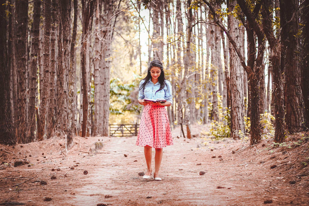 A woman taking a nature walk with a book in her hand