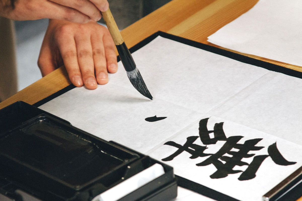 A individual creating traditional calligraphy with ink and brush