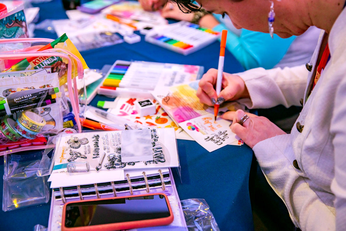 A woman decorating her journal page using Artistry by Altenew water-based brush pens for coloring