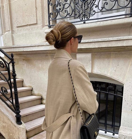 Elegant old money woman with her hair neatly tied in a low bun at the nape of her neck.