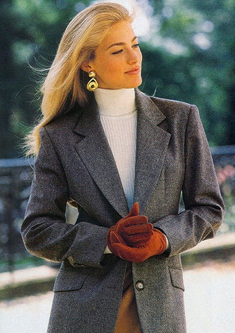 Attractive young woman dressed in old money winter fashion, including a blazer, turtleneck, and gloves.