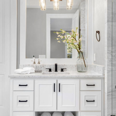 A white bathroom vanity with sink and light