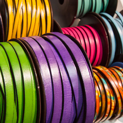 Spools of dyed leather straps in bright colors.