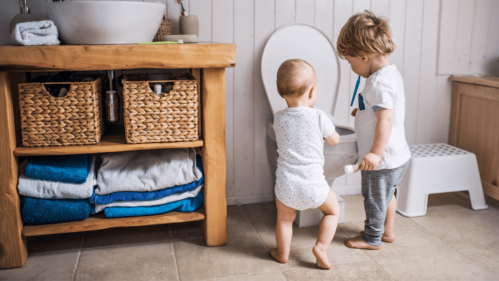 2 enfants en train d'apprendre la propreté aux toilettes