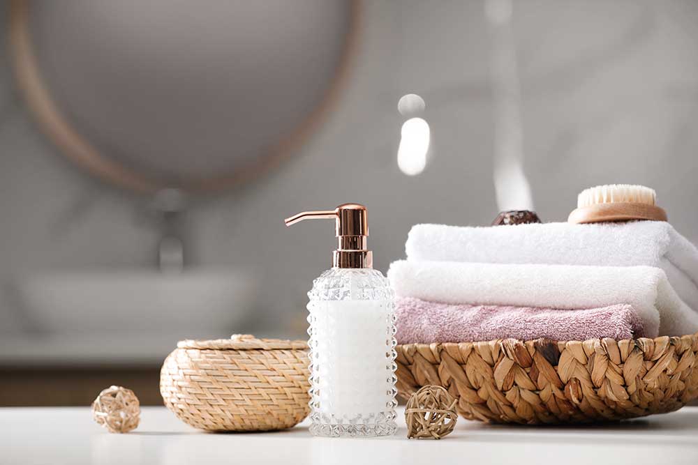 Soap dispenser, towels and brush on white table indoors