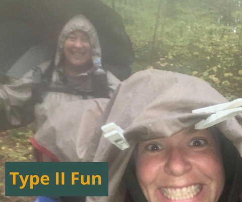 2 women hiking and smiling in the rain. Type II fun.