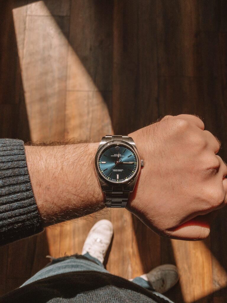 A man in casual clothes with a Rolex on his watch looking at it from a first person perspective.