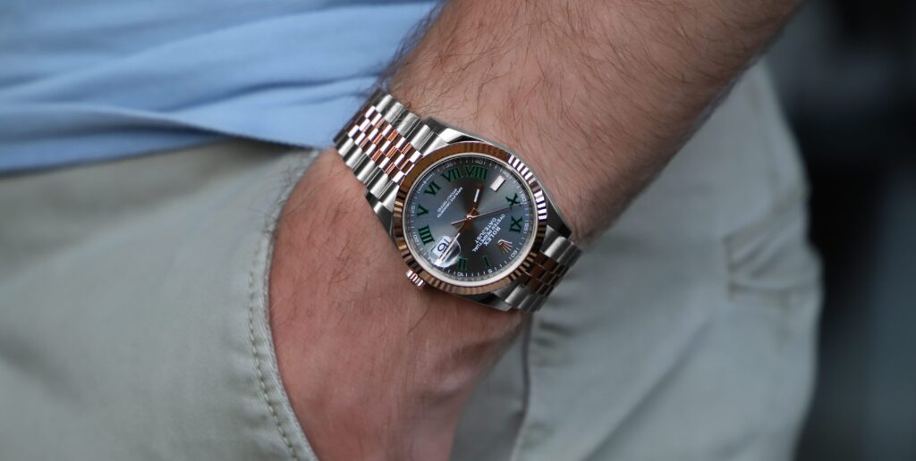 A man wearing a Rolex watch with his hand in his pocket.