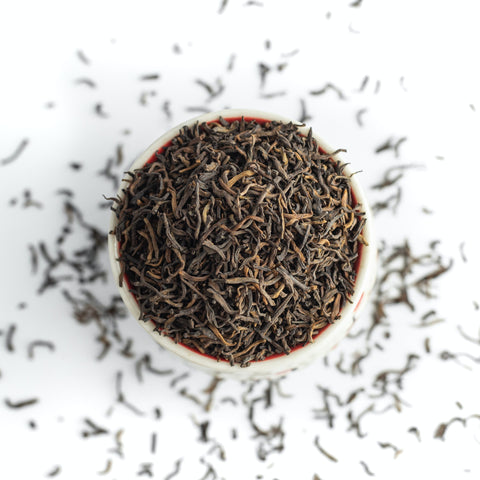 Tea leaves in white container on white background with tea scattered around:Photo by petr sidorov on Unsplash