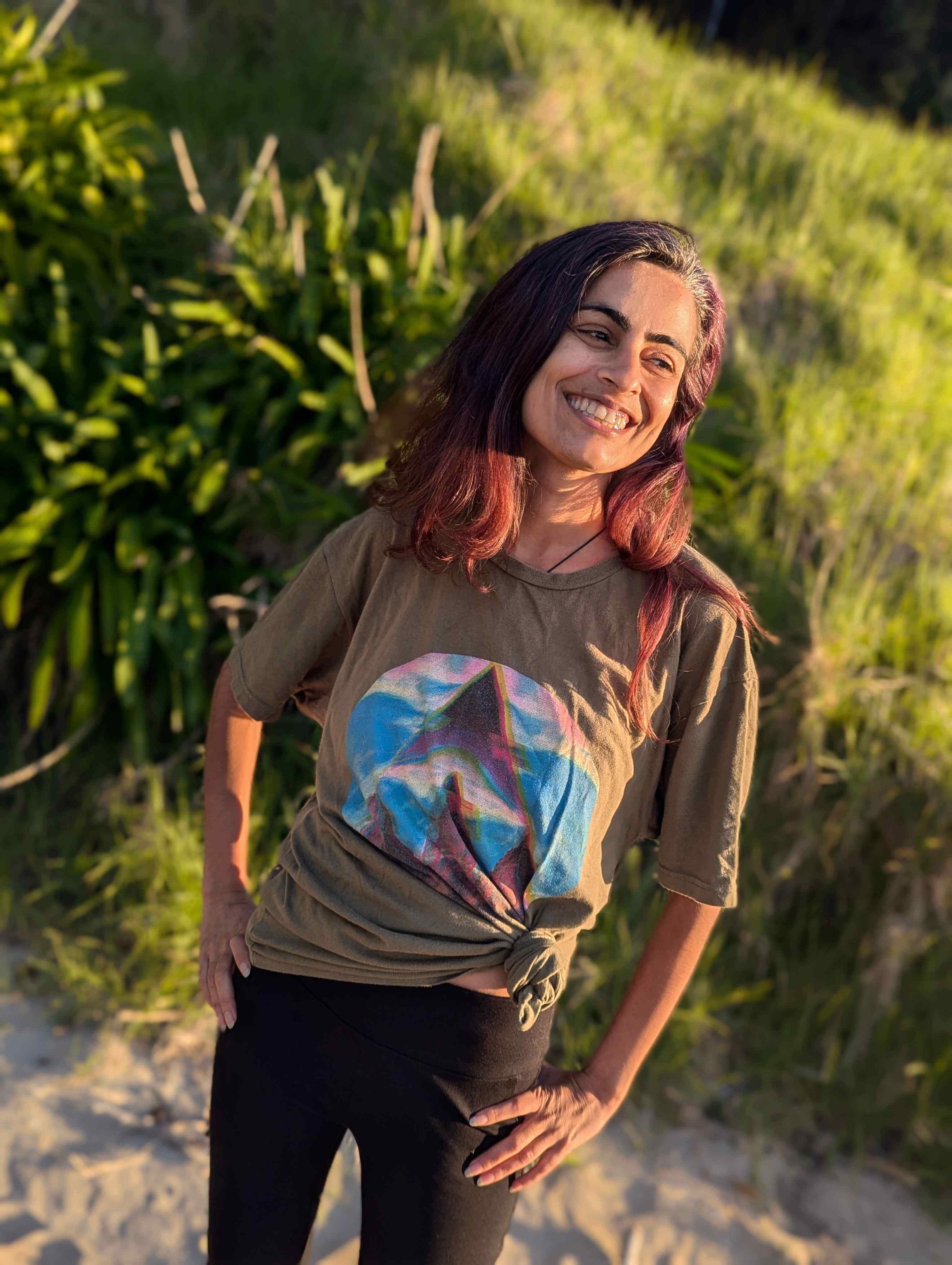 Zasha flowing through a pose in Waiheke Island, New Zealand, wearing the Wyld Peak Fusion tee – movement, balance, and style