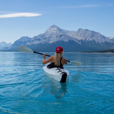 Photo d'une kayakiste sur un lac devant un paysage magnifique