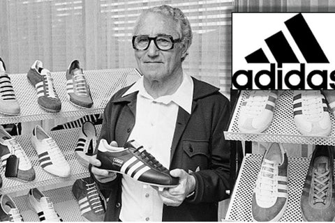 Photo d'Adolf Dassler portant une chaussure de football noire Adidas