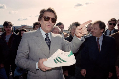 Photo de Bernard Tapie en train de porter une chaussure Adidas blanche et verte