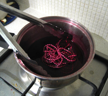 Strand of freshwater pearls being dyed ina utensil