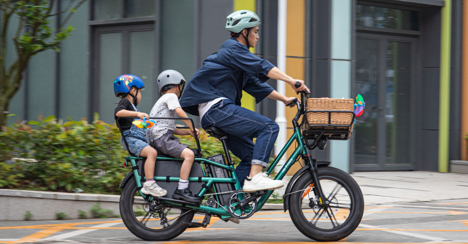 Un homme conduit un Fiido T2 Longtail cargo E-bike avec deux enfants à l'arrière.