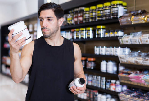 Tienda de suplementos; hombre eligiendo entre dos suplementos distintos