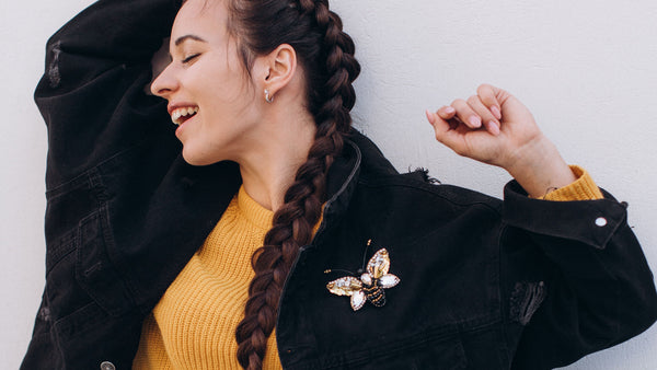 Young woman wearing bee brooch on black denim jacket