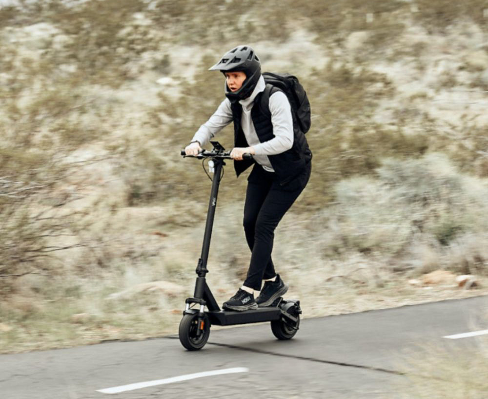 Une jeune femme qui roule sur un VMAX VX4 dans un paysage montagneux en portant un casque.