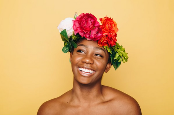 Woman smiling with a flower crown after using beauty products from a clean beauty brand.