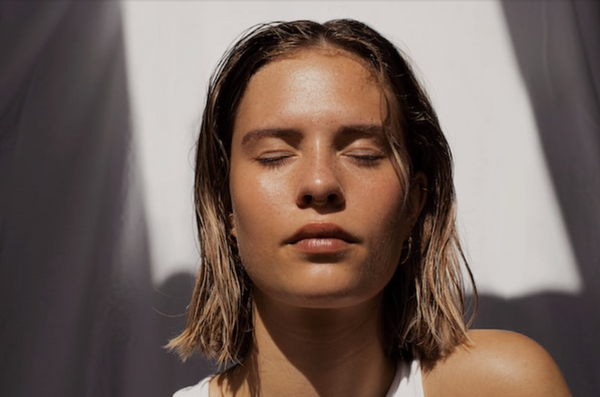 A woman with light, tanned skin shows off her natural clean beauty style.