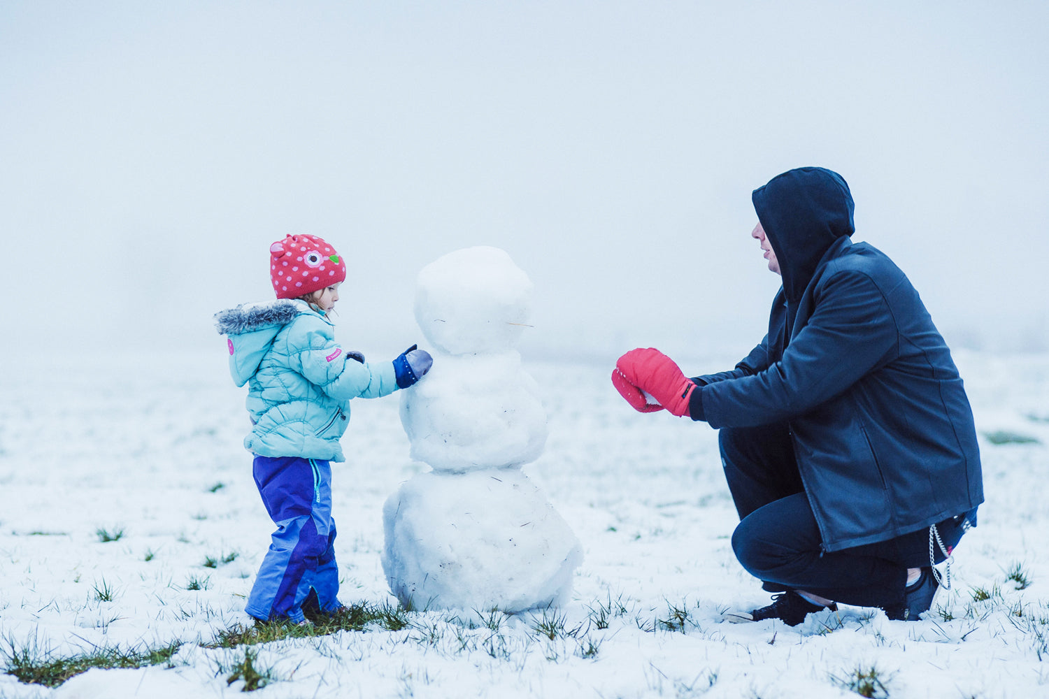 A Young Boy & His Father Building a Snowman