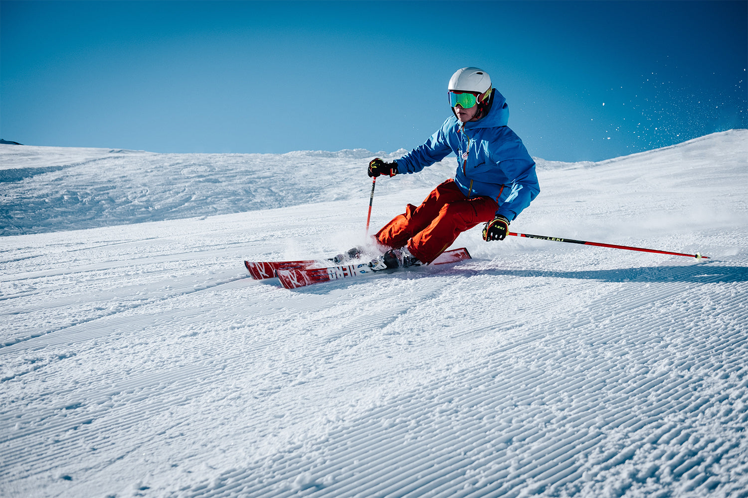 A Man In Winter Gear Skiing Down A Slope