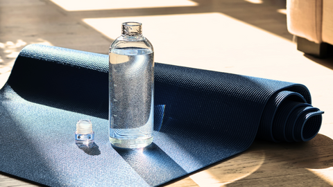 This image showcases a clear, glass water bottle strategically placed on a partially rolled-up yoga matt. This image is used in the Ippodaro Natural Salon blog titled, “Unhealthy Scalp: Red Flags to Watch Out For and How to Treat Them”.