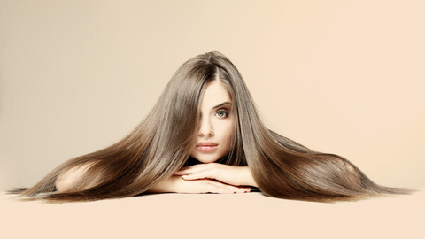 This is an image of a beautiful, long-haired brunette, laying on her stomach, with her luxurious hair, parted to the side, cascading over her arms, onto the ground. This image is used in the Ippodaro Natural Salon blog post titled, “If You Want Luxurious Hair, You CAN NOT Overlook an Oily Scalp”.