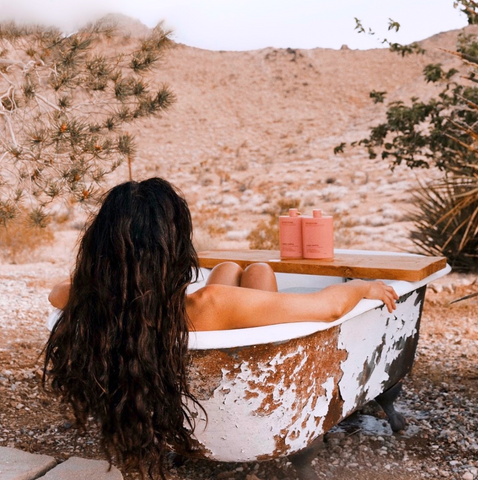 This is an image of a gal sitting in a rustic, outdoor bathtub in the dessert. Her hair is cascading over the back of the bathtub. This is a Routine image showcasing their Sexy Sadie shampoo and conditioner. This image is then used in the Ippodaro Natural Salon blog post titled, “Exploring the Essentials: The Magic of Shampoo & the Best Options for YOUR Hair”.