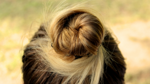 This is a photo of a woman wearing her hair in a top bun in an effort to protect her hair from the sun. This photo is used in the Ippodaro Natural Salon blog post titled, “Mastering Summer Hair Care: Top Tips for Healthy Hair”.