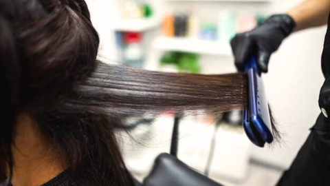 This is an image of a stylist flatironing hair after performing a keratin treatment on their client. This image is used in the Ippodaro Natural Salon blog post titled, “The Dangers of Traditional Keratin Treatments and Different Options Offered at Ippodaro Natural Salon”.