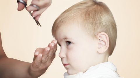 This is an image of a young, boy, toddler getting his hair trimmed. This image is used in the Ippodarro Natural Salon Blog Post titled, “There are So Many Hairstyles for Kids! Here are Some Ideas, Tips, and Tricks for the 2023 School Season!