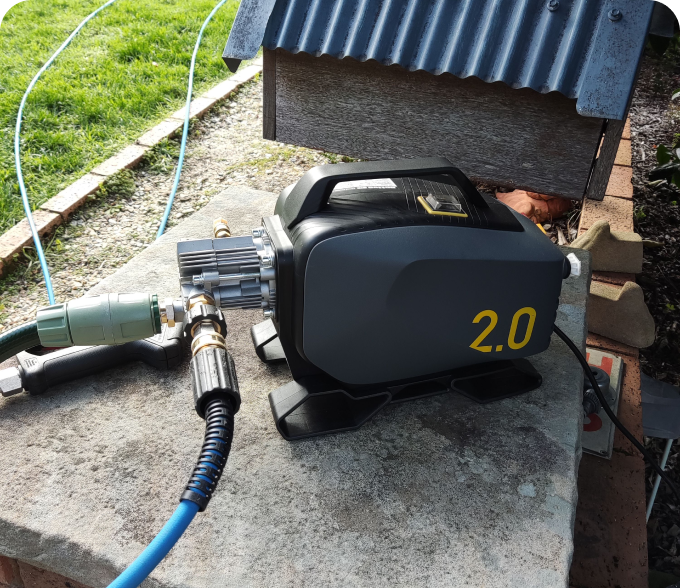Electric water pressure pump with hose connections on a concrete surface.