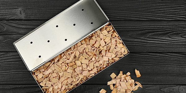 A stainless steel smoker box filled with smoking wood chips