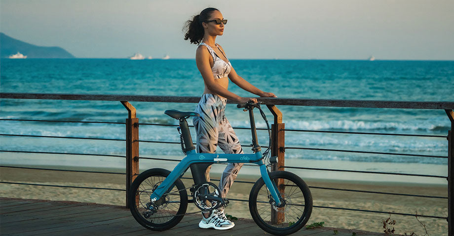 Frau fährt Elektrofahrrad und parkt am Straßenrand am Strand