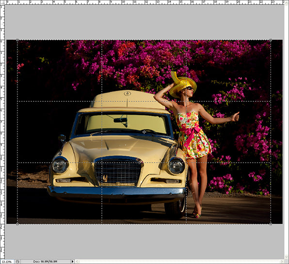 Woman in a floral dress modeling next to a yellow classic car