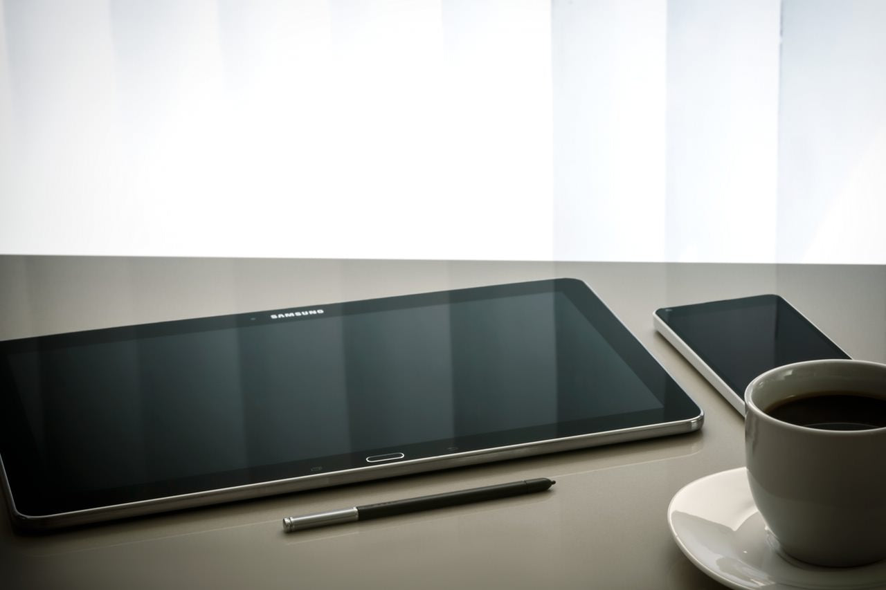 Samsung tablet and phone sitting next to a cup of coffee