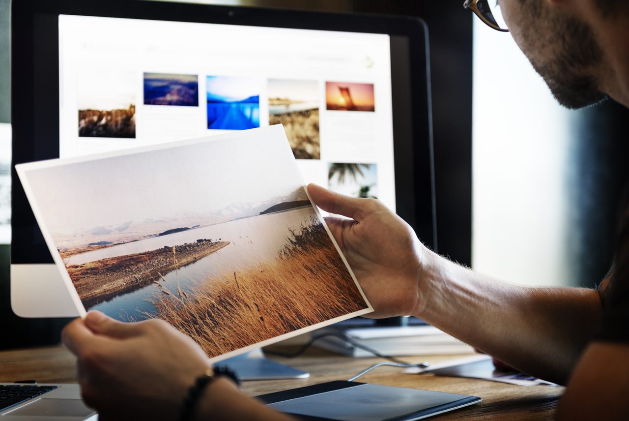 Artists holding a printed artwork of a winding river