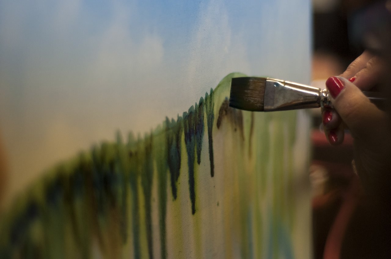Artist using a brush to paint on a canvas