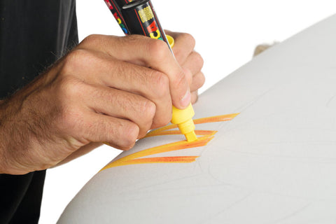 Artist using yellow Posca paint on surfboard to show how it can be blended