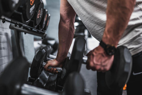  man grabbing a pair of dumbbells