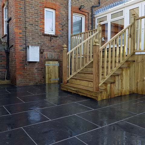 black limestone patio with wooden stairs leading down to it