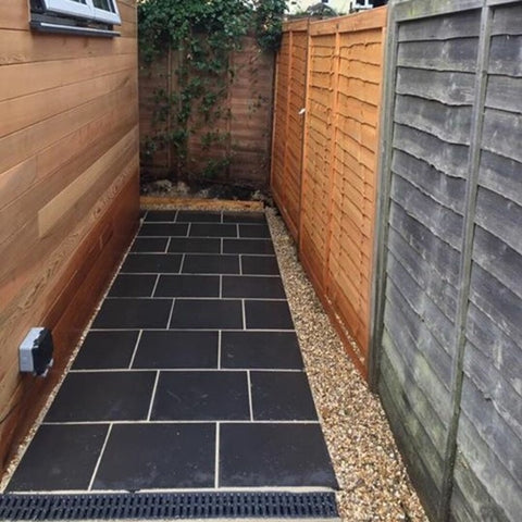 thin black limestone patio using square 60cm x 60cm down the side of a house