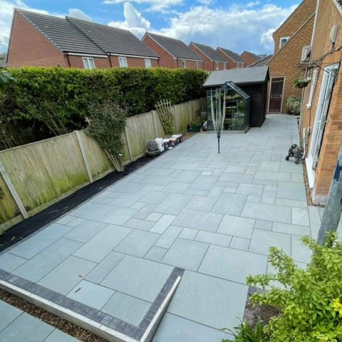 kota blue limestone paving slab patio. Long and thin patio with a brown shed at the back