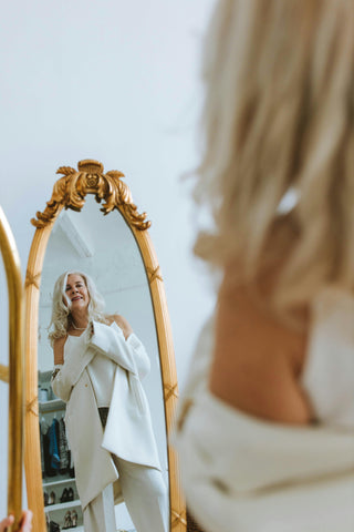 Ouder vrouw kijkt blij in een staande spiegel