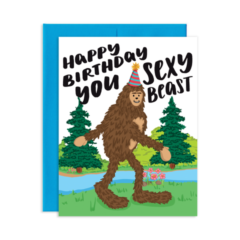 Birthday greeting card with blue envelope. The greeting card has an illustration of big foot in aparty had walking though a forest of pine trees.