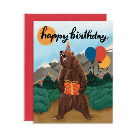 Birthday greeting card with a red envelope. Birthday card has a roaring grizzly bear in the forest. The bear is holding a birthday present and the tree's are decorated with party streamers.