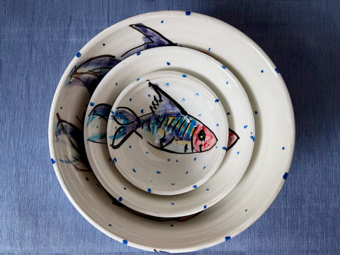 Three handmade ceramics pottery bowls nested together on a blue tablecloth. Each bowl is handmade and handprinted with a mackerel fish motif in celebration of the Wild Atlantic Way of Ireland. Handmade by Charlie Mahon Ceramics Pottery in Cork, Ireland. Authentic Irish souvenir.