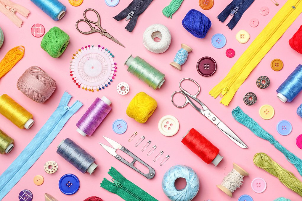 Image of craft tools used in sewing, such as scissors and snippers, displayed with thread and other sewing items.