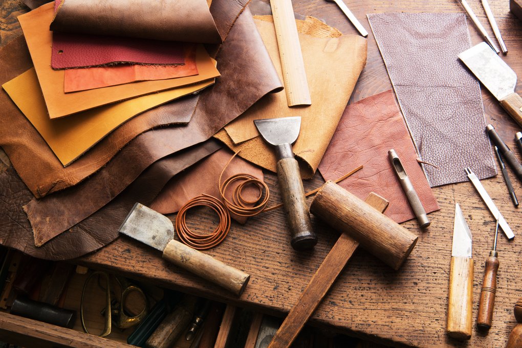 Leather pieces and leather cutting tools displayed on workbench
